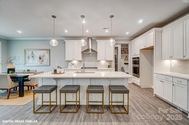 kitchen with wall chimney range hood, light countertops, tasteful backsplash, white cabinetry, and recessed lighting