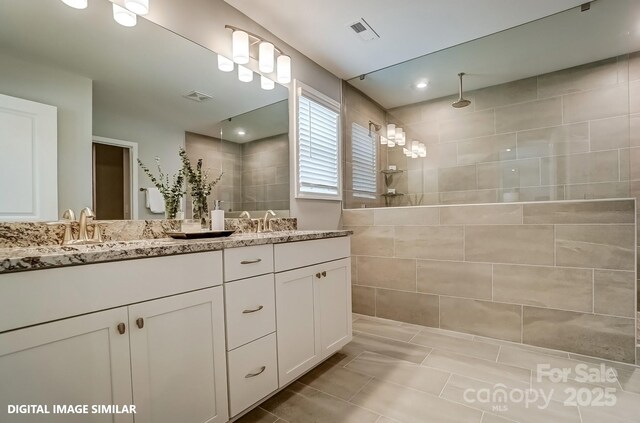 bathroom featuring double vanity, a walk in shower, and tile patterned flooring