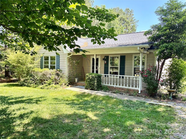 single story home with a porch, a front lawn, and roof with shingles