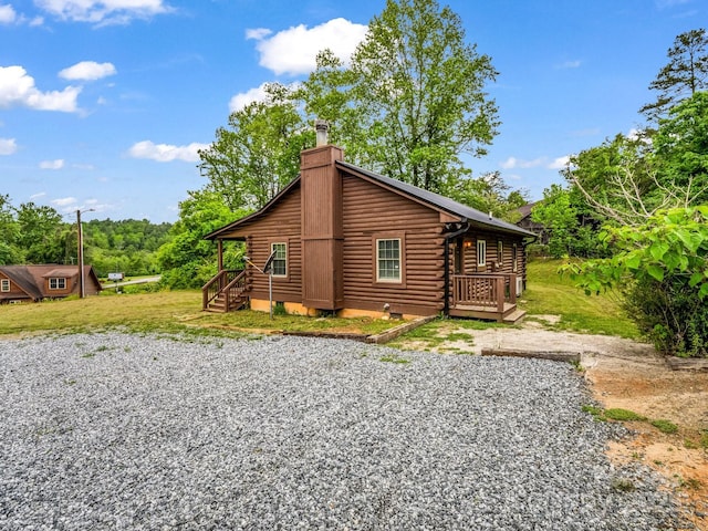 back of house featuring log exterior, crawl space, a chimney, and a wooden deck