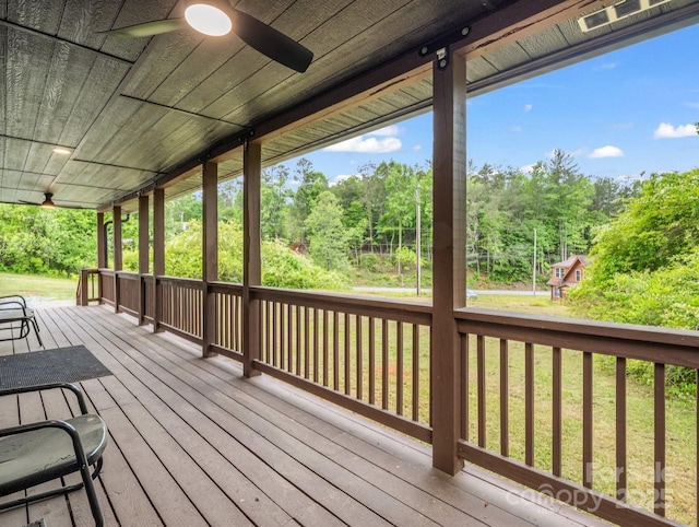 wooden deck featuring ceiling fan, a forest view, and a porch
