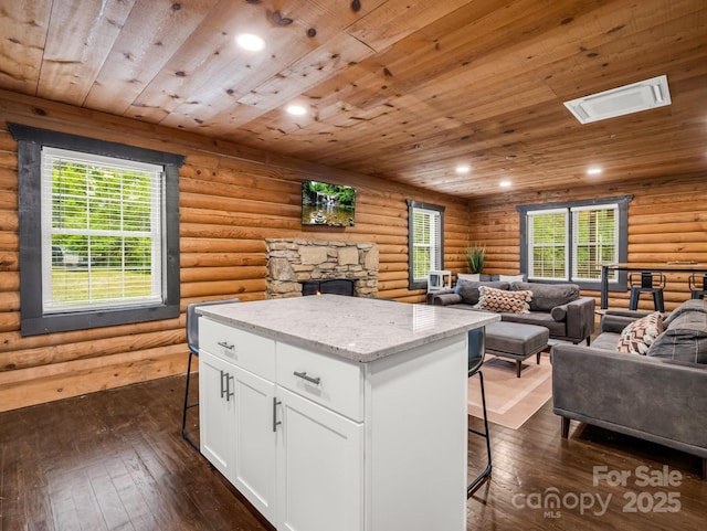 kitchen featuring open floor plan, a breakfast bar, rustic walls, white cabinetry, and a center island