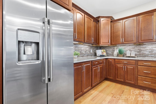 4616 Gold Finch Dr, Denver, NC 28037 - kitchen with stainless steel fridge with ice dispenser, light wood-style floors, light stone countertops, tasteful backsplash, and brown cabinetry