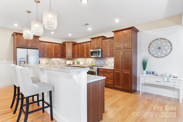 4616 Gold Finch Dr, Denver, NC 28037 - kitchen with high end appliances, light wood-style flooring, a breakfast bar area, an island with sink, and pendant lighting
