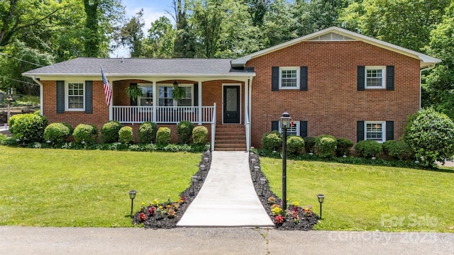 tri-level home with covered porch, a front lawn, and brick siding