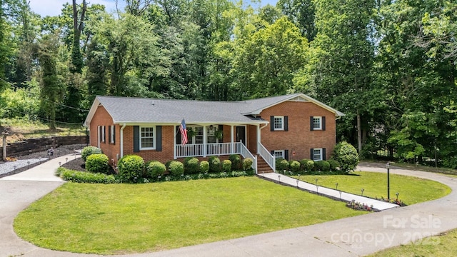 split level home with a porch, brick siding, a front yard, and concrete driveway