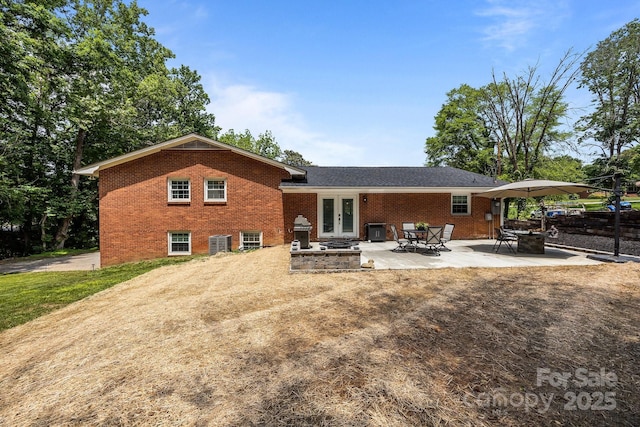 back of house featuring french doors, brick siding, cooling unit, and a patio area