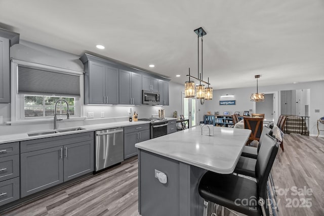 kitchen featuring a sink, appliances with stainless steel finishes, gray cabinets, light wood-style flooring, and recessed lighting