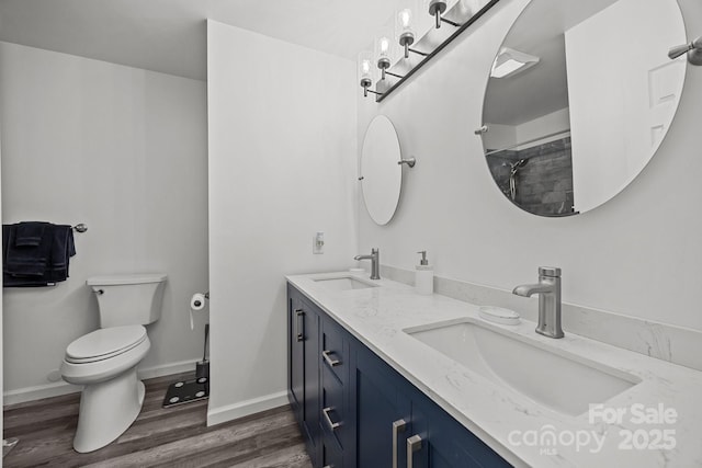 full bathroom featuring toilet, wood finished floors, a shower, double vanity, and baseboards