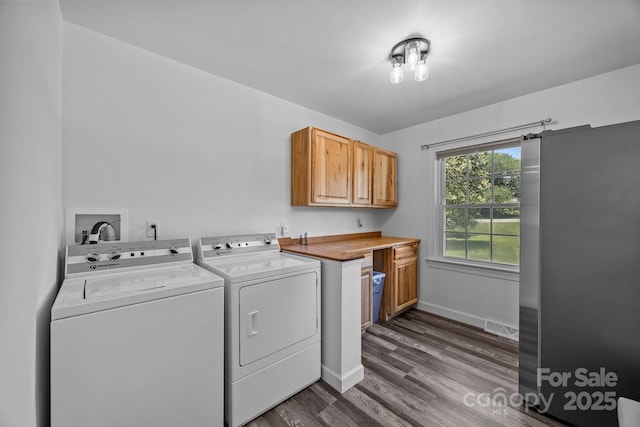 clothes washing area with independent washer and dryer, cabinet space, dark wood-style flooring, and baseboards