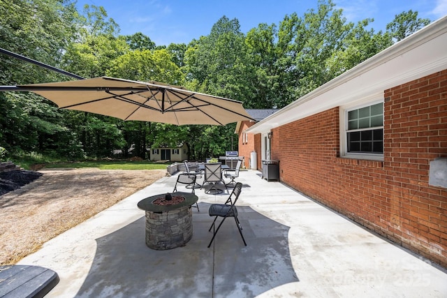 view of patio / terrace with a fire pit, an outbuilding, outdoor dining area, and view of scattered trees