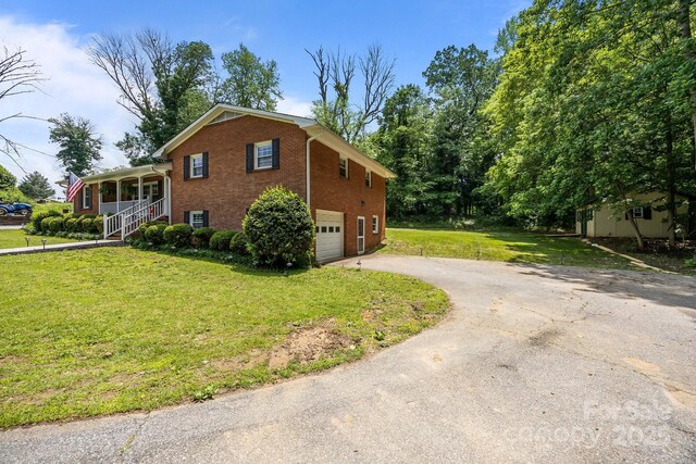 view of home's exterior featuring brick siding, driveway, a garage, and a yard