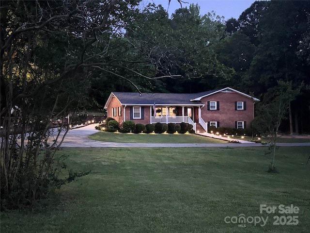 2076 Junction Rd, Mocksville, NC 27028 - view of front of property with covered porch, a front lawn, brick siding, and concrete driveway