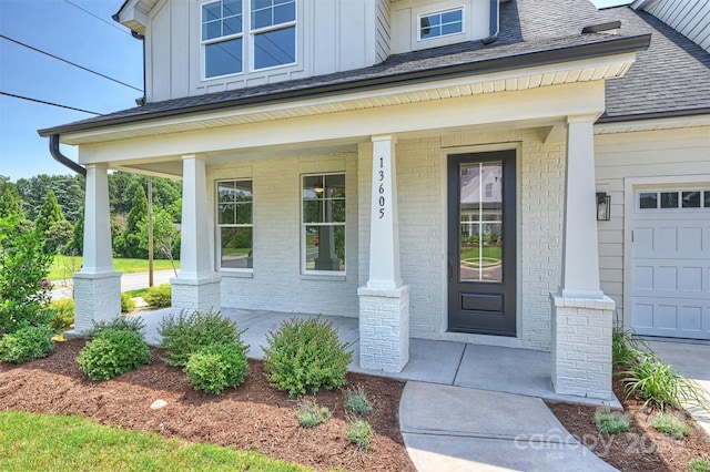 13605 Tranquil Day Dr, Matthews, NC 28105 - view of exterior entry featuring board and batten siding, a porch, brick siding, a garage, and a shingled roof