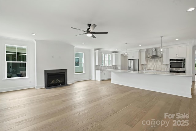 13605 Tranquil Day Dr, Matthews, NC 28105 - unfurnished living room with recessed lighting, a fireplace with flush hearth, ceiling fan, and light wood-style floors