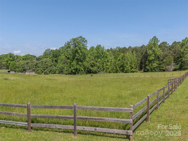 view of yard featuring fence, a view of countryside, and a view of trees