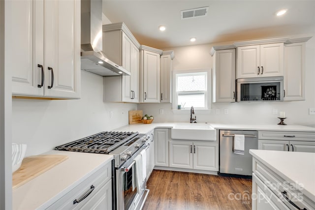 18011 Wilbanks Dr, Charlotte, NC 28278 - kitchen featuring stainless steel appliances, wall chimney exhaust hood, a sink, wood finished floors, and light countertops
