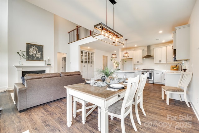 18011 Wilbanks Dr, Charlotte, NC 28278 - dining space with wood finished floors, baseboards, a fireplace, recessed lighting, and a towering ceiling