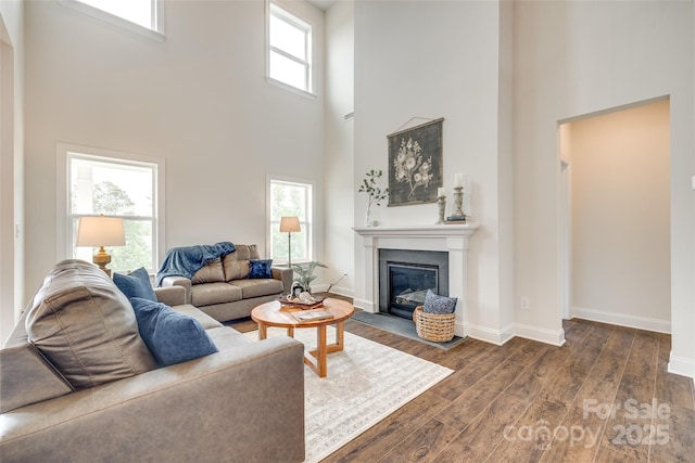 18011 Wilbanks Dr, Charlotte, NC 28278 - living area featuring a towering ceiling, dark wood-style floors, a fireplace with flush hearth, and baseboards