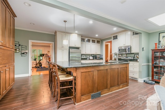 408 Idlewood Dr, Kannapolis, NC 28083 - kitchen featuring appliances with stainless steel finishes, dark wood-style flooring, baseboards, ornamental molding, and an island with sink