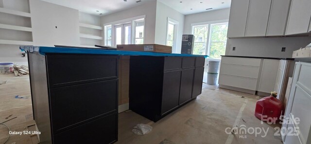 kitchen with dark cabinets and concrete flooring