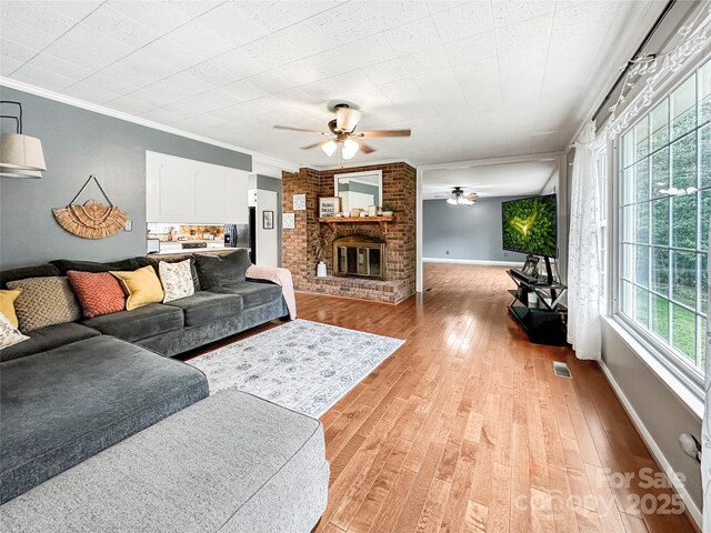 200 Woodside Dr, Morganton, NC 28655 - living area with a ceiling fan, ornamental molding, light wood-style flooring, a brick fireplace, and baseboards