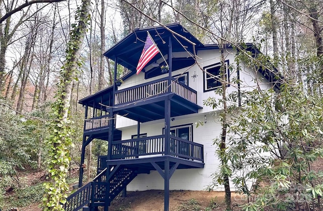 back of property featuring a balcony, stairs, and concrete block siding