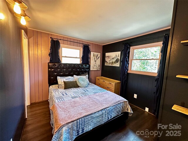 bedroom featuring wood finished floors, multiple windows, wooden walls, and crown molding