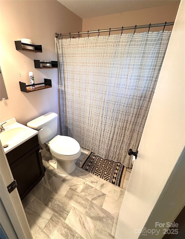 bathroom with toilet, vanity, and a shower with shower curtain