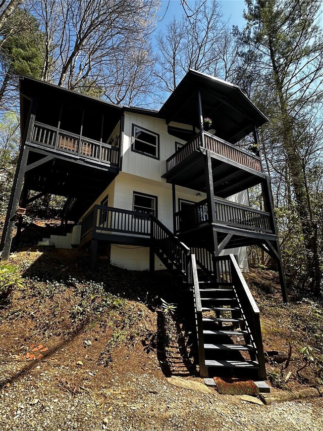 back of property featuring stairway, a balcony, and a wooden deck