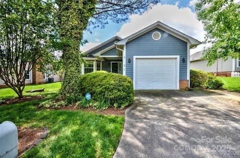 single story home featuring an attached garage, concrete driveway, and a front lawn