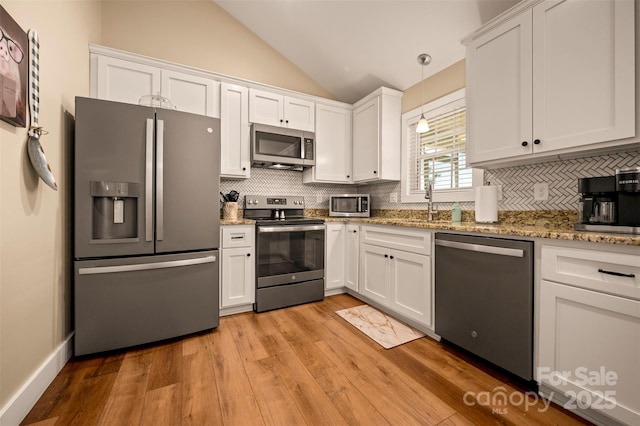 105 Kingston Pl, Spindale, NC 28160 - kitchen with stainless steel appliances, lofted ceiling, white cabinetry, backsplash, and light wood-type flooring