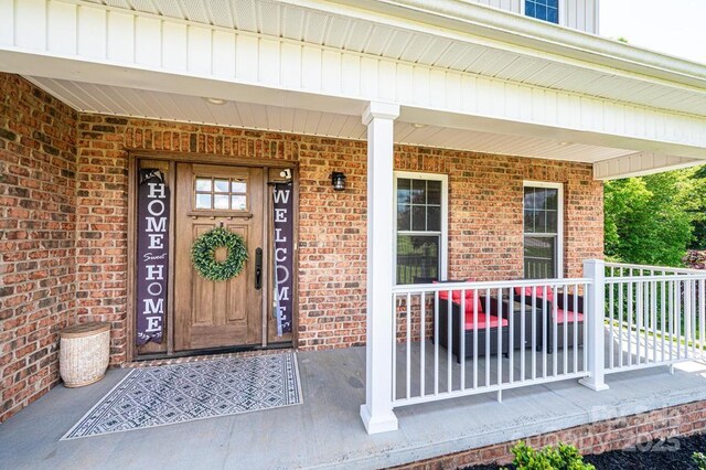 property entrance with brick siding and a porch