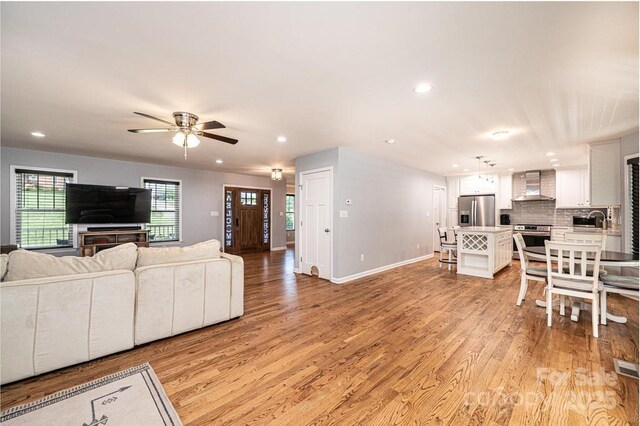 living room with recessed lighting, ceiling fan, light wood-type flooring, and baseboards