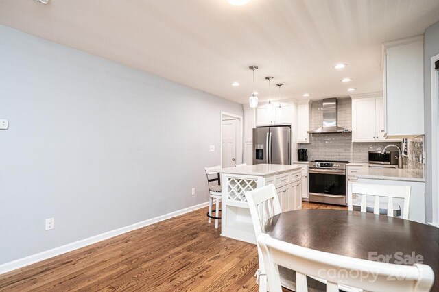 kitchen with stainless steel appliances, wall chimney exhaust hood, a sink, backsplash, and light countertops
