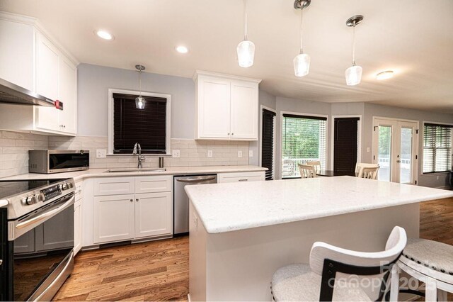 kitchen featuring stainless steel appliances, a sink, light wood-type flooring, a breakfast bar area, and tasteful backsplash
