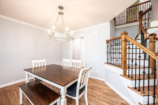 dining room with a chandelier, stairs, ornamental molding, wood finished floors, and baseboards