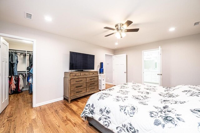 bedroom with light wood-type flooring, a walk in closet, a closet, baseboards, and recessed lighting