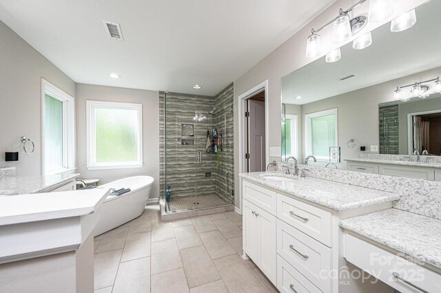 full bathroom with a shower stall, tile patterned flooring, a freestanding bath, two vanities, and recessed lighting