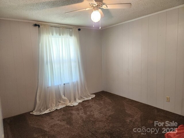 carpeted empty room featuring a textured ceiling, a ceiling fan, and ornamental molding