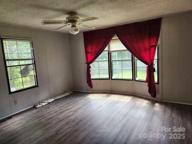 unfurnished room featuring wood finished floors, plenty of natural light, a textured ceiling, and ceiling fan