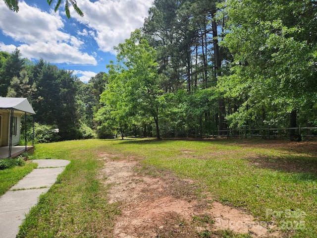 view of grassy yard with a forest view