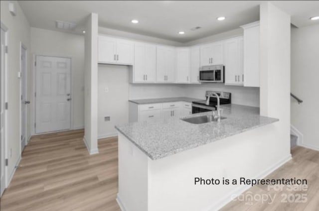 487 Shasta St Unit 5203, Gastonia, NC 28052 - kitchen with appliances with stainless steel finishes, a peninsula, light wood finished floors, white cabinetry, and recessed lighting