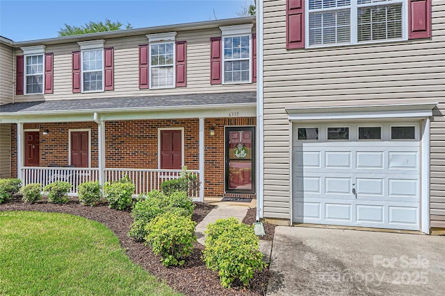6335 Ziegler Ln, Charlotte, NC 28269 - townhome / multi-family property with a porch, a garage, brick siding, and driveway