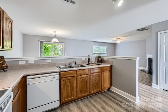 6335 Ziegler Ln, Charlotte, NC 28269 - kitchen with white appliances, brown cabinets, a sink, light wood-style flooring, and healthy amount of natural light