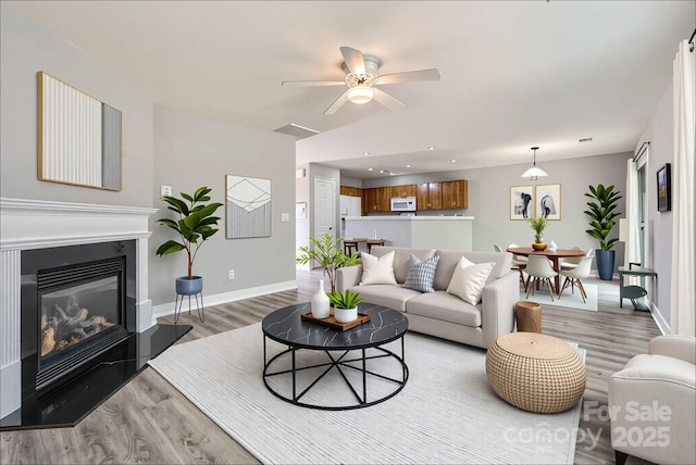6335 Ziegler Ln, Charlotte, NC 28269 - living room featuring light wood finished floors, ceiling fan, baseboards, a glass covered fireplace, and recessed lighting