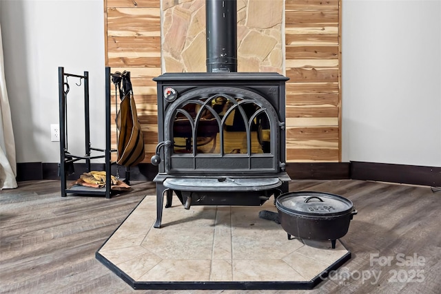 detailed view of a wood stove, wood finished floors, and baseboards