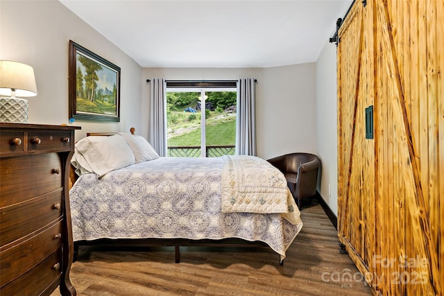 bedroom with wood finished floors, a barn door, and access to exterior