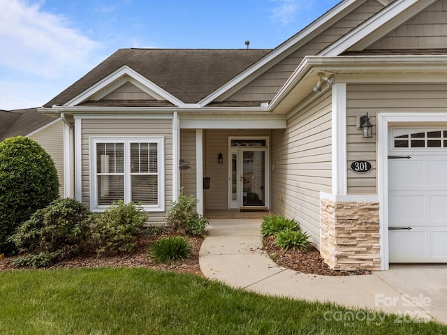 301 Garner Dr, Salisbury, NC 28146 - view of exterior entry with a garage, a shingled roof, and stone siding