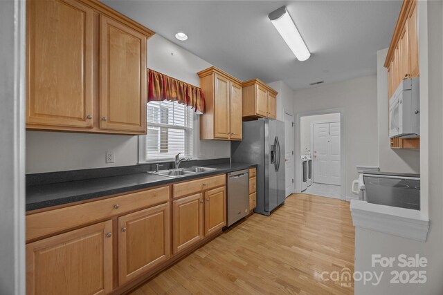 301 Garner Dr, Salisbury, NC 28146 - kitchen with appliances with stainless steel finishes, a sink, light wood-type flooring, dark countertops, and washer / dryer